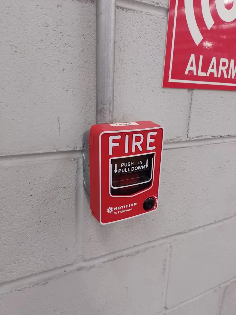 Estación manual roja de la marca Notifier instalada en pared para activar alarmas de incendio.