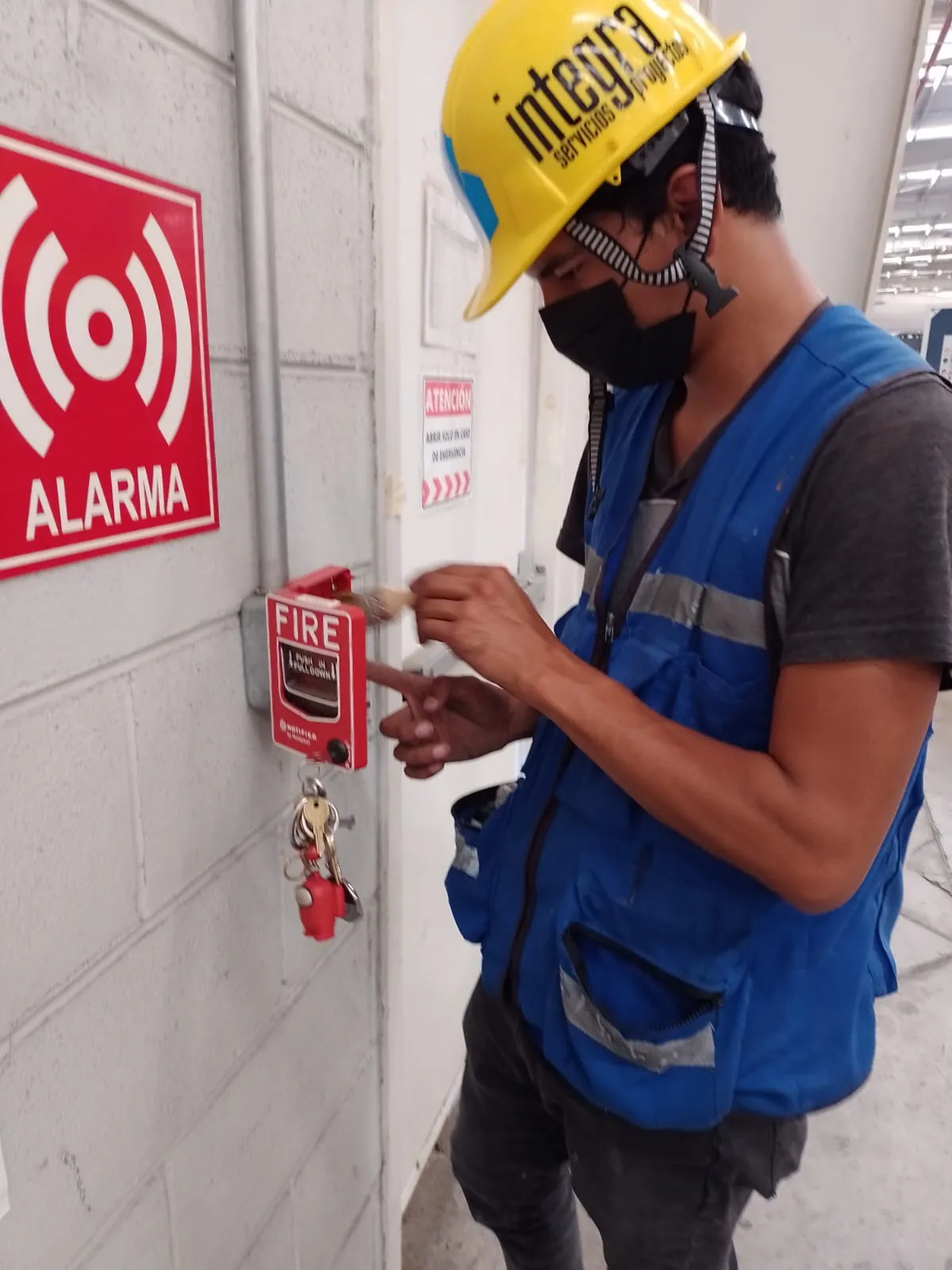 Especialista usando multímetro para medir voltaje en fuente de poder de alarmas de incendio y baterías.