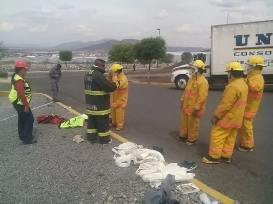 Personal revisando uniformes y equipo de protección para las brigadas contra incendios frente a un almacén de carga.